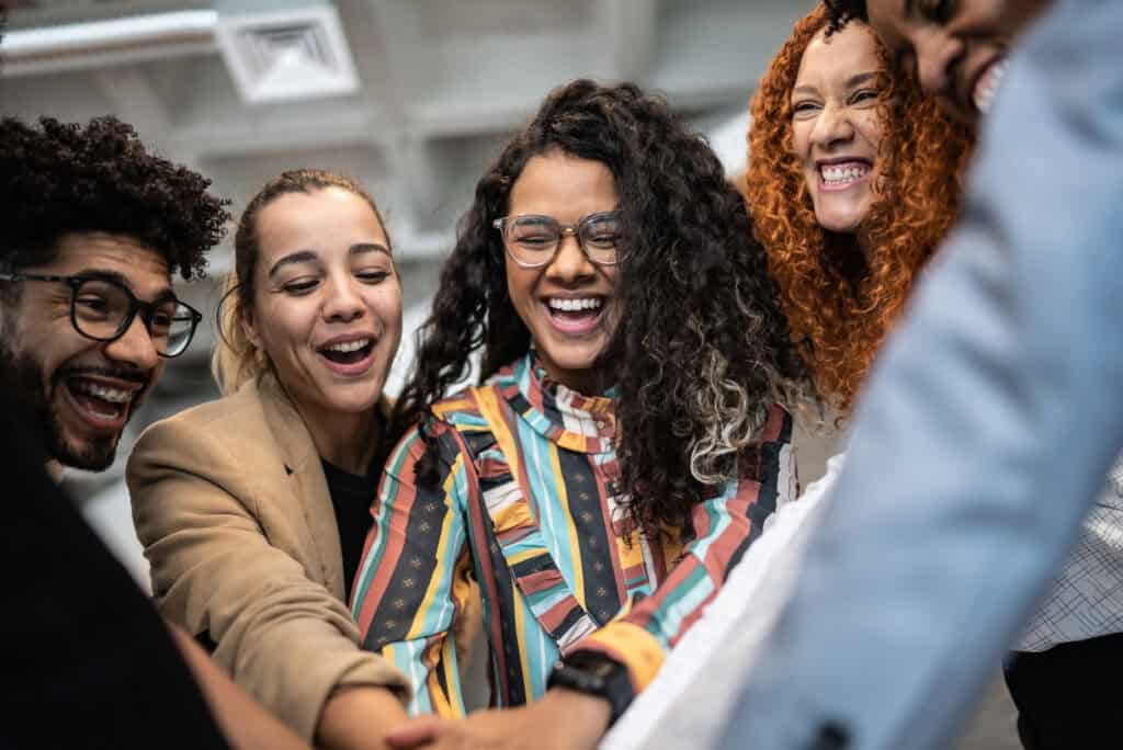 A team of cheerful coworkers with their hands stacked together