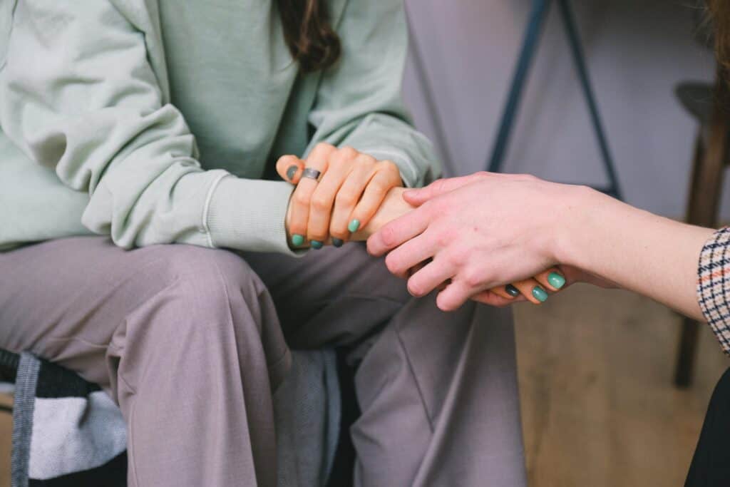 The photo shows a person's hands being held in a showing of support by another.