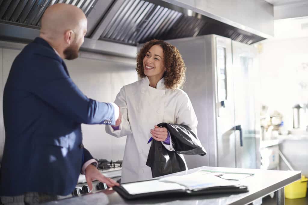 A chef shaking hands with her workplace employer