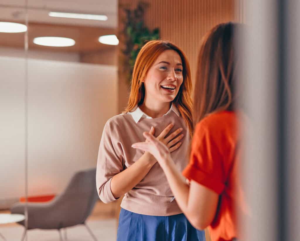 Two colleagues chat in a bright, modern office