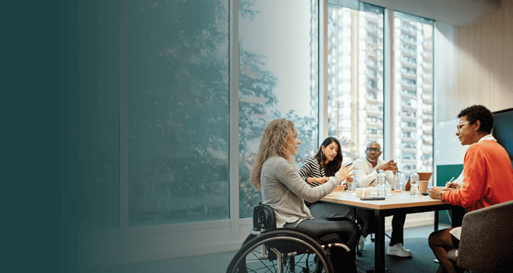 Employee in a wheelchair talking to coworkers in a meeting room.