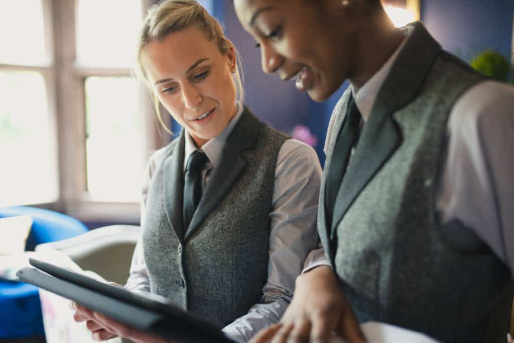 Two hotel staff are talking and working together.