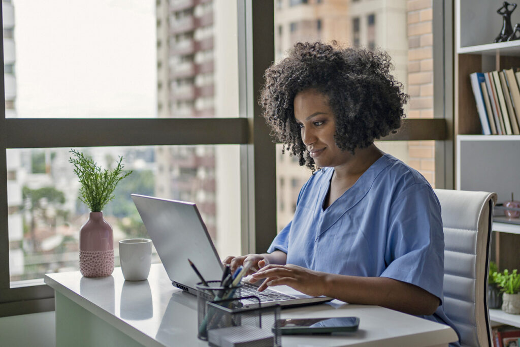 Nurse looking at her laptop computer in her home office