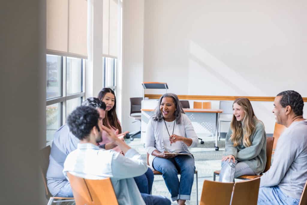 Diverse group of people sitting in a circle talking and laughing