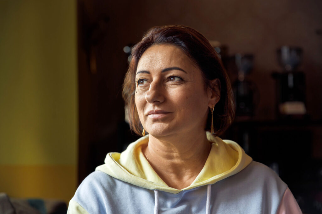 Thoughtful woman in cozy sweatshirt looking away in soft natural light
