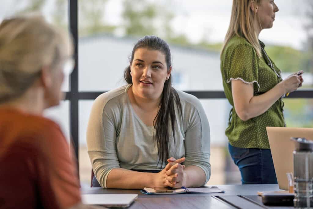 Woman sitting at a boardroom table, sharing her ideas with her coworkers