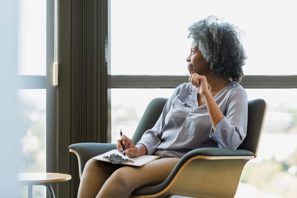 Mature black woman counsellor sitting and thinking between sessions.