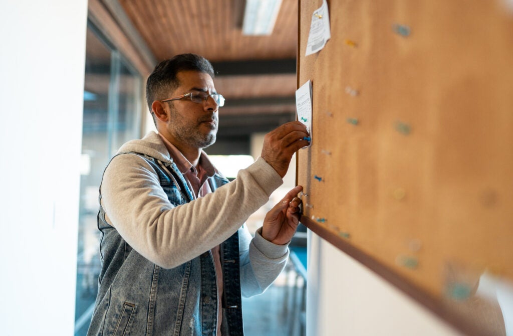 Social worker putting up information on a bulletin board.