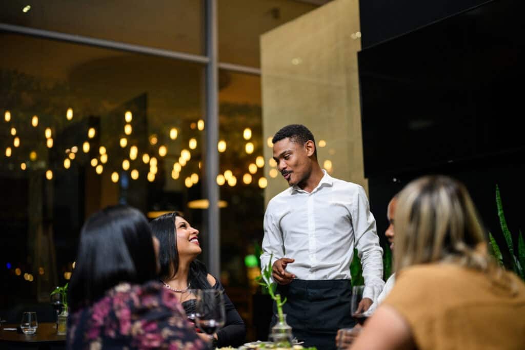 Waiter talking to a group of friends enjoying a holiday gathering