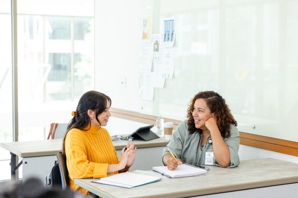 A supervisor smiling and giving feedback to a fellow worker
