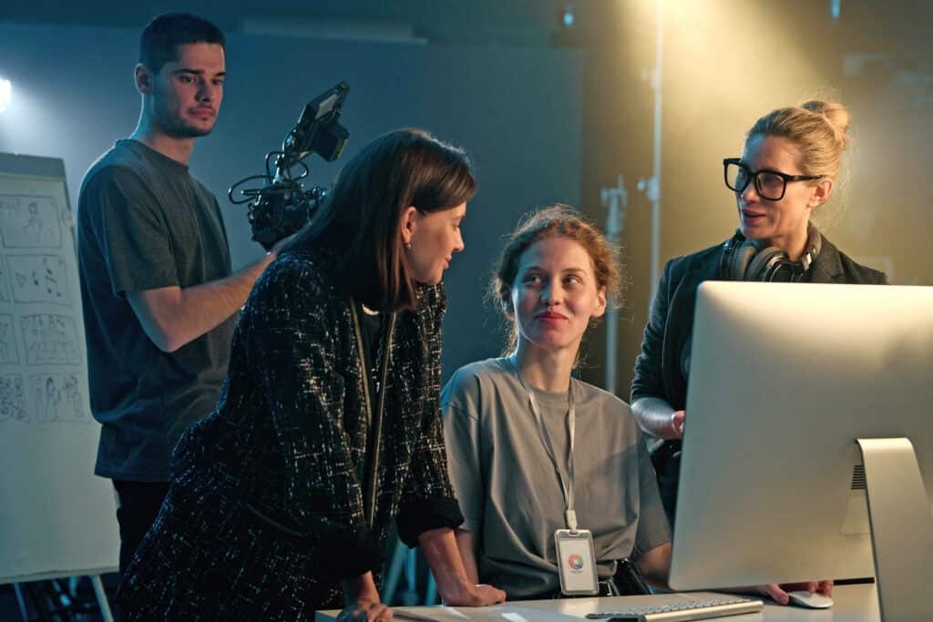 Portrait of video production crew reviewing footage and using com.puter on set smiling