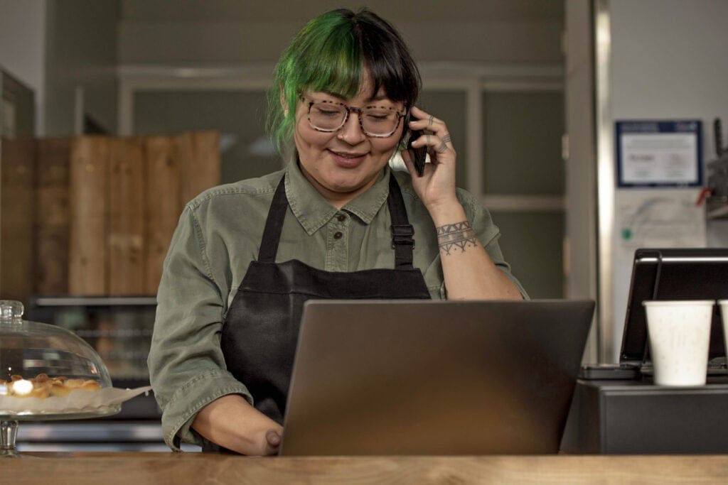 Young indigenous cafe worker talks on the phone with a customer