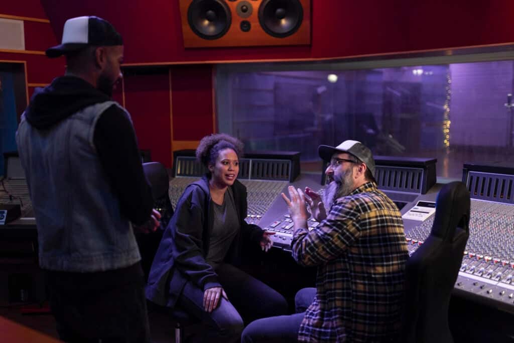 Mature male composer talking with singers in recording studio.