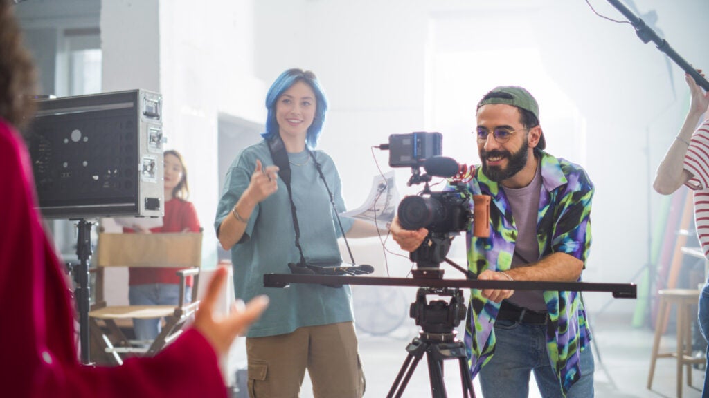 Young camera operator smiling while working under pressure.
