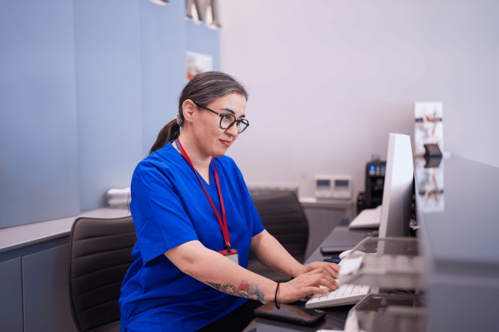 Nurse with a focused look on her face, inputting information into a computer.