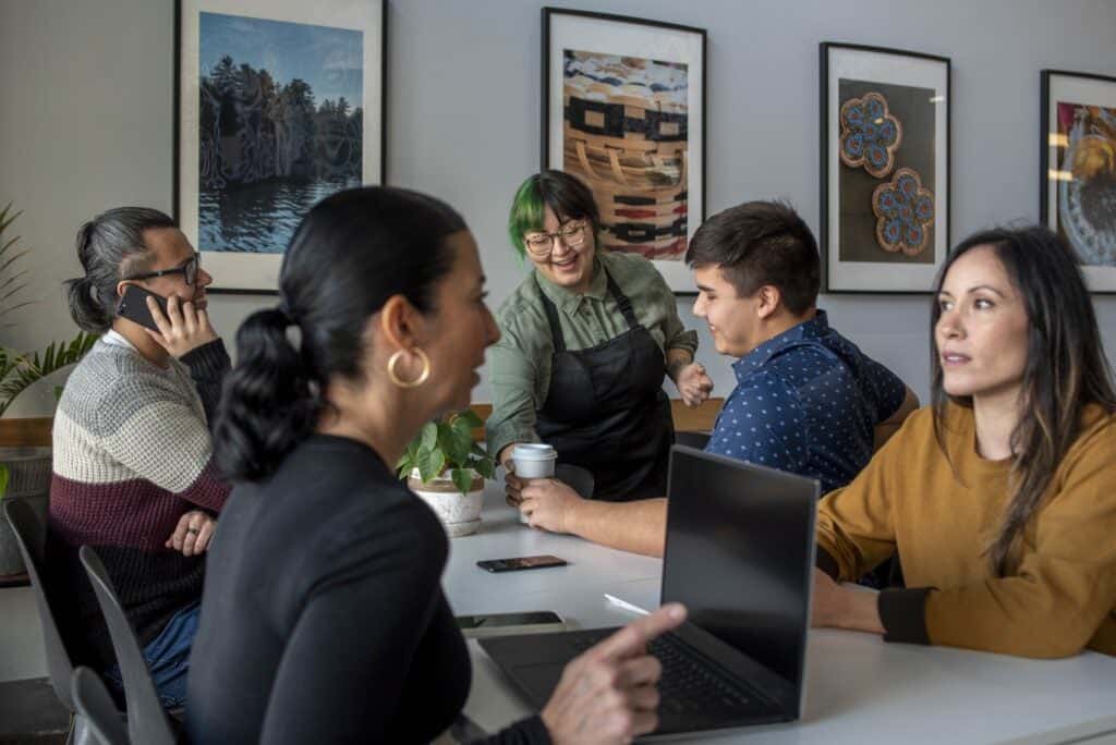 Young indigenous barista brings coffee to indigenous customer.