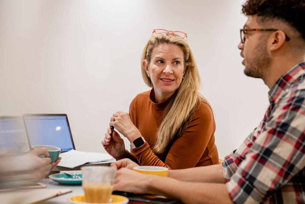 Social workers having a serious discussion. The woman on the left is looking at the main on the right, waiting for her turn to speak.