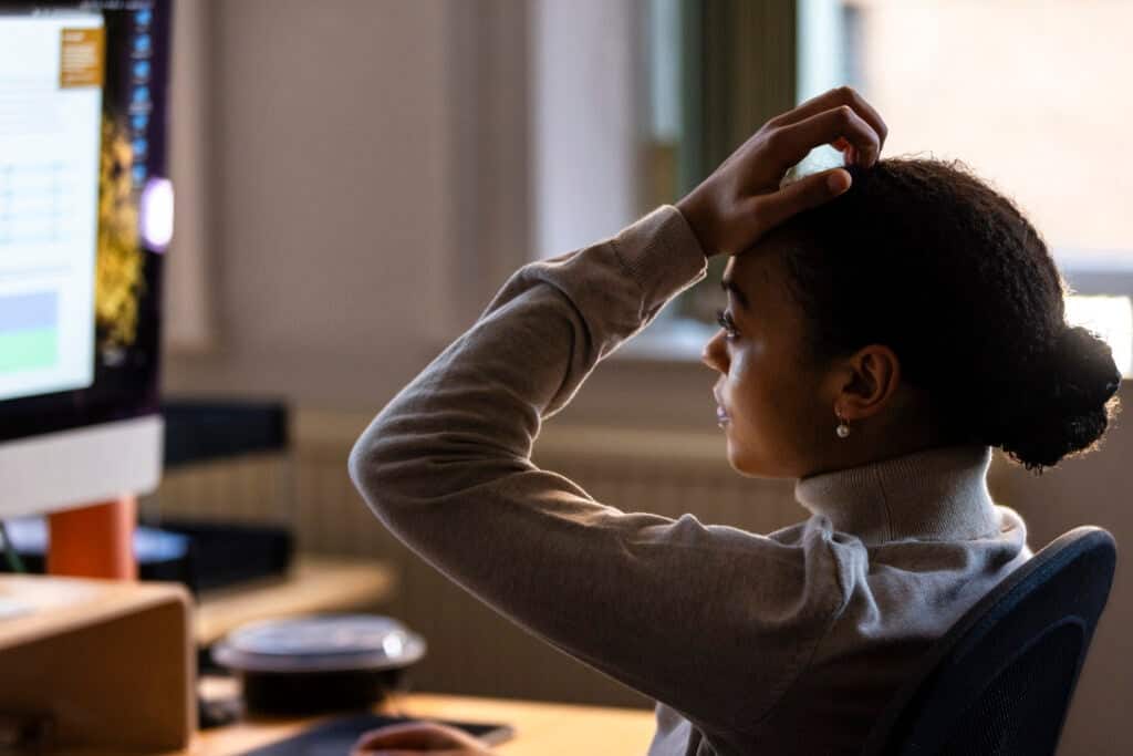 Social worker sitting at her desk holding her hand to her head because she is feeling overwhelmed