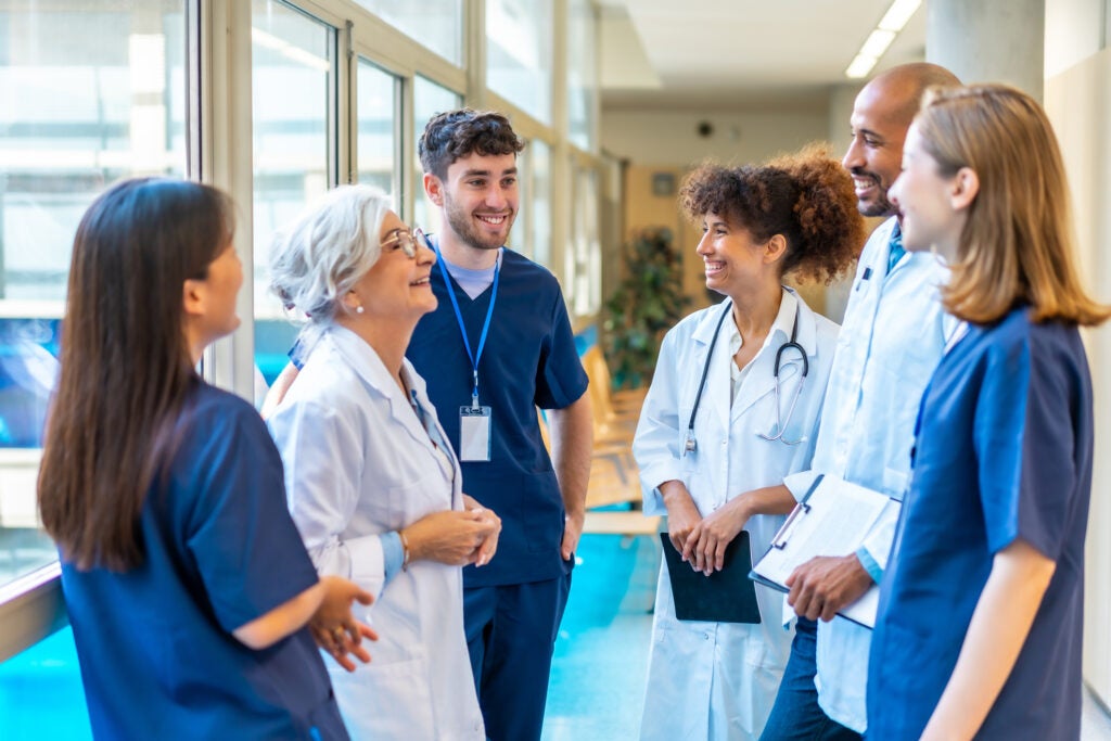 Doctors and nurses standing together in a hospital corridor, engaging in conversation and sharing smiles.