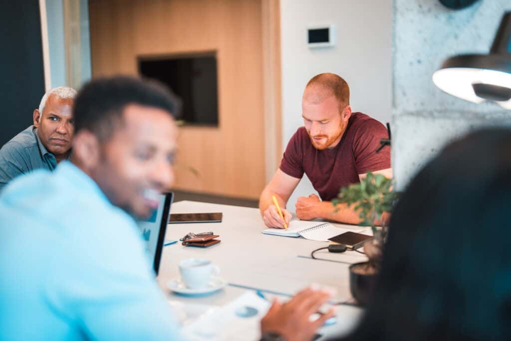 Social worker sitting at a table with coworkers taking notes