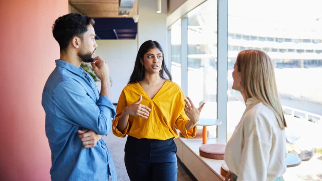 Woman gesturing with her hands, explaining a concept to her coworkers.